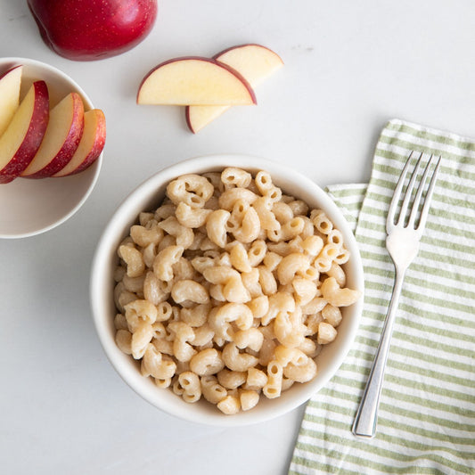 Jovial Gluten Free White Cheddar Mac and Cheese in a bowl, served with pasta and cheese sauce, on a wooden table.