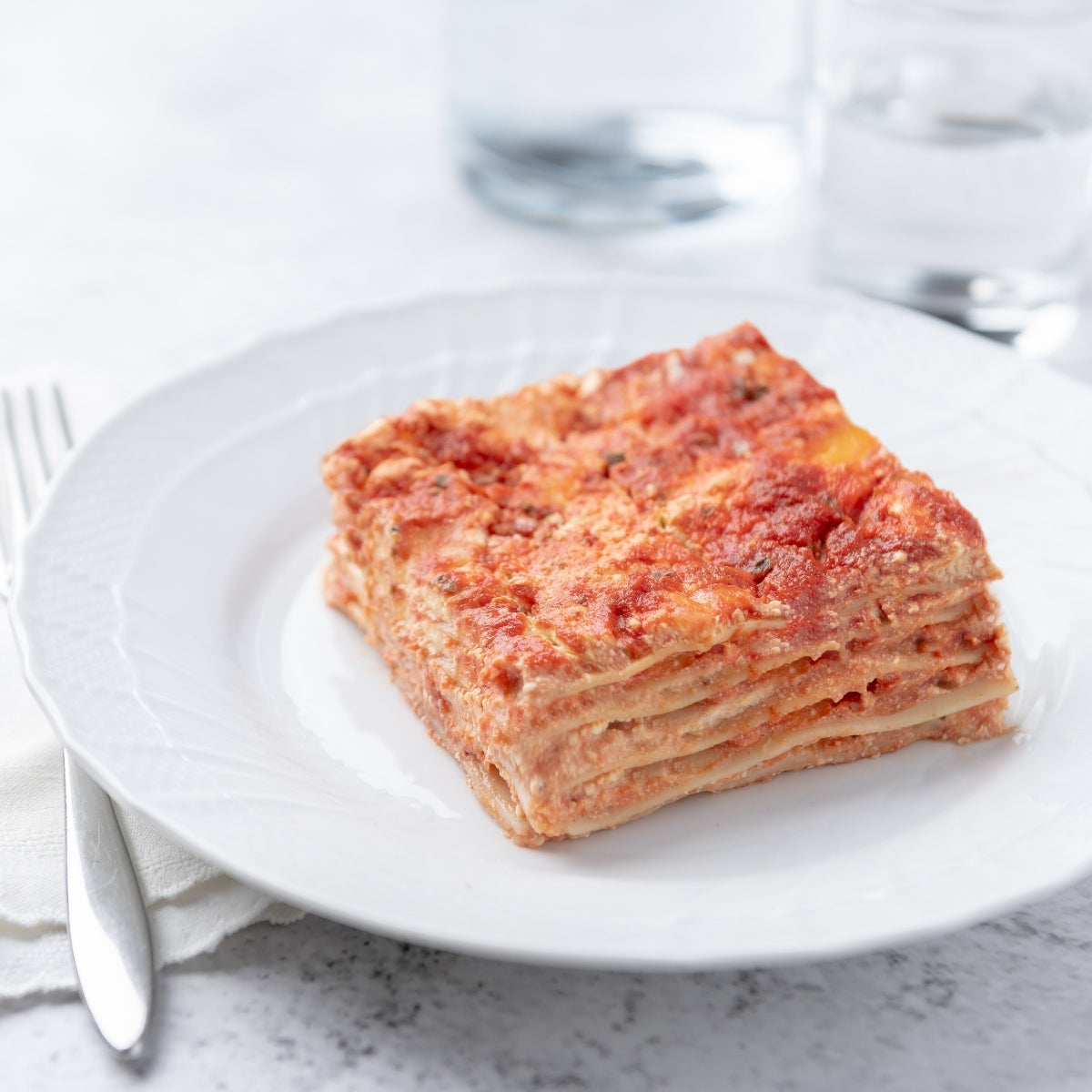 Gluten-free Jovial Brown Rice Classic Lasagna with layers of pasta, cheese, and tomato sauce in a baking dish.