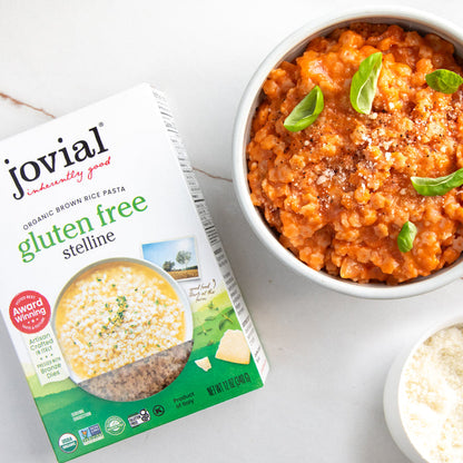 Gluten-free Jovial brown rice stelline pasta with tomato sauce, natural Italian pasta shape served on a white plate.