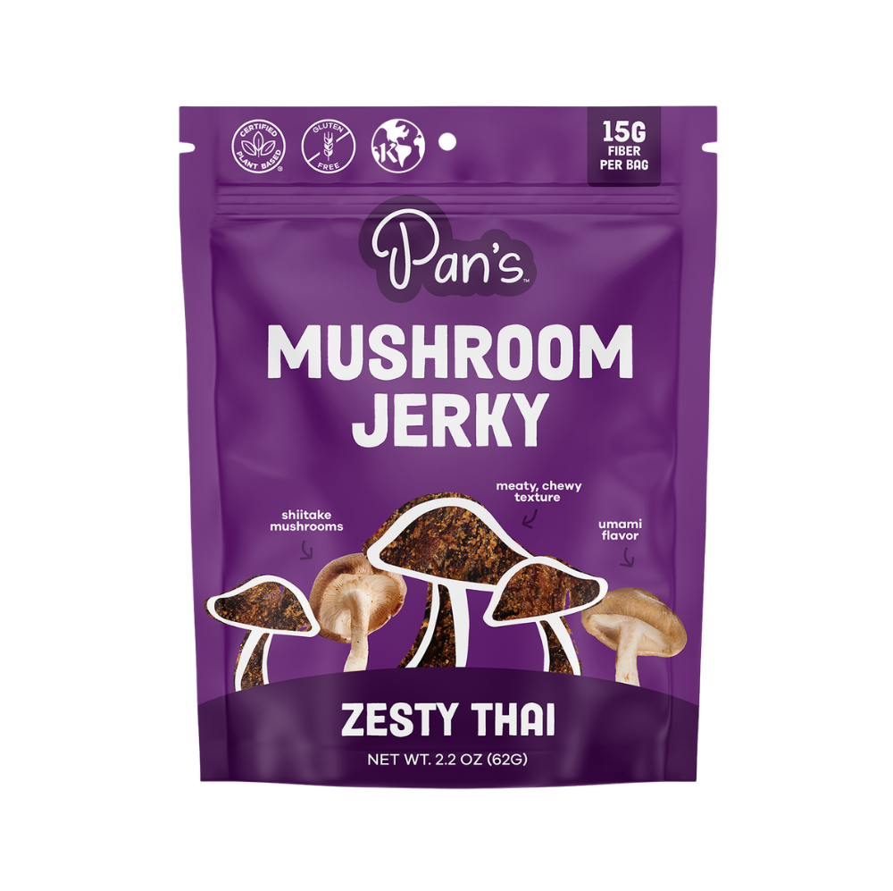 Pan's Mushroom Jerky Thai Mushroom Snack Foods with zesty flavor, dried mushroom slices on a rustic wooden surface.
