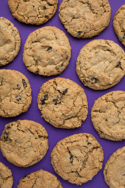 Ethel's Baking Company oatmeal raisin cookies, a close-up of two freshly baked cookies with raisins on a rustic surface.