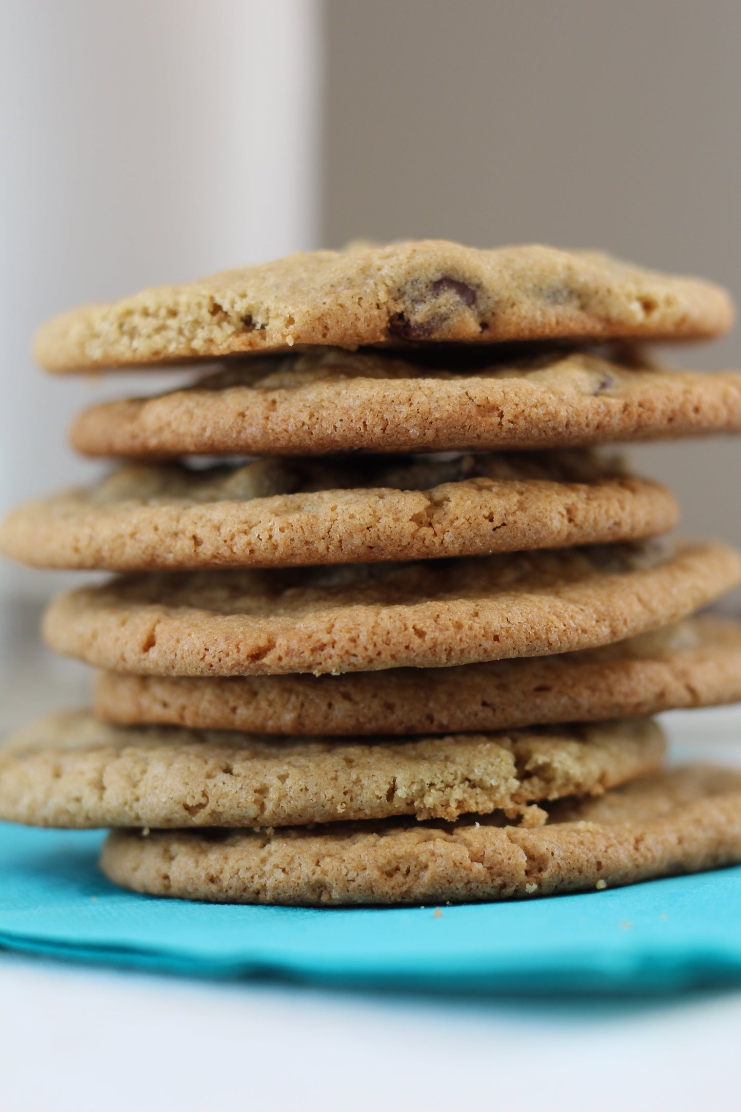 Close-up of Jessica's Natural Foods chocolate chip cookie mix in a tall, clear jar with a wooden scoop, showcasing the product's packaging.