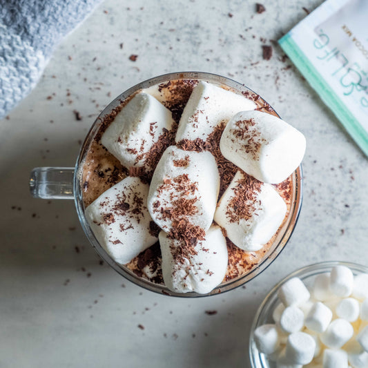 Bare Life dairy-free coconut hot cocoa mix in a mug topped with marshmallows, showcasing the vegan gluten-free hot cocoa.