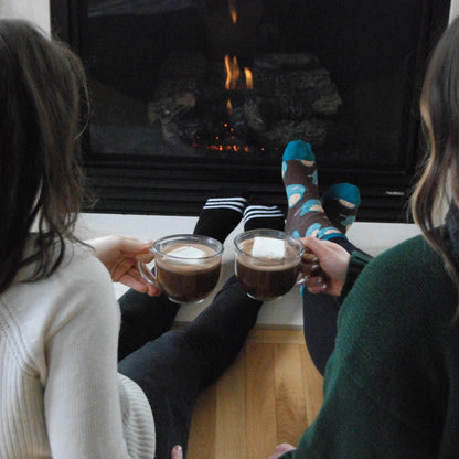 Bare Life dairy-free coconut hot cocoa mix in a mug topped with marshmallows, set in front of a holiday fire.