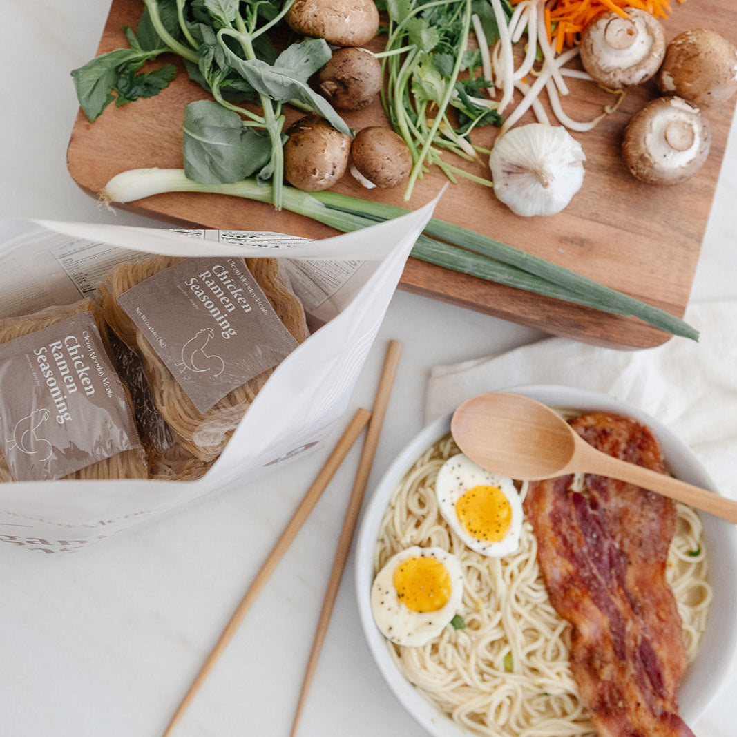 Pack of Clean Monday Meals Ramen Noodles in a clear plastic container with steaming hot noodles and broth visible.