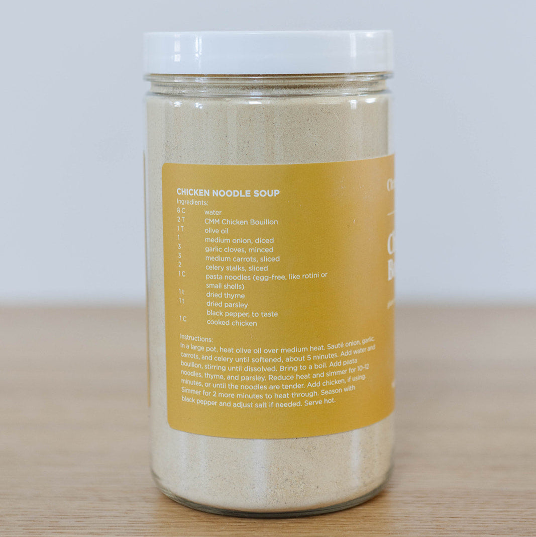 Container of Clean Monday Meals Chicken Bouillon seasoning, featuring a clear label and lid, used to enhance soups and dishes.