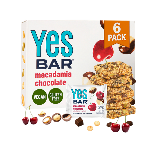 YES BAR Macadamia Chocolate energy bars, six-pack, showing chocolate-coated bars with macadamia nuts inside.