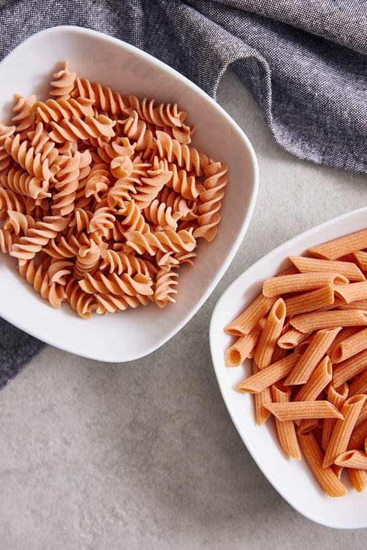 Six-pack of Flower Chef Foods artisanal gluten-free pasta featuring penne and fusilli shapes in clear packaging.