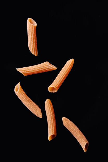 High protein Flower Chef Foods penne pasta in a clear glass bowl, showcasing its textured, cooked pasta shape on a white background.
