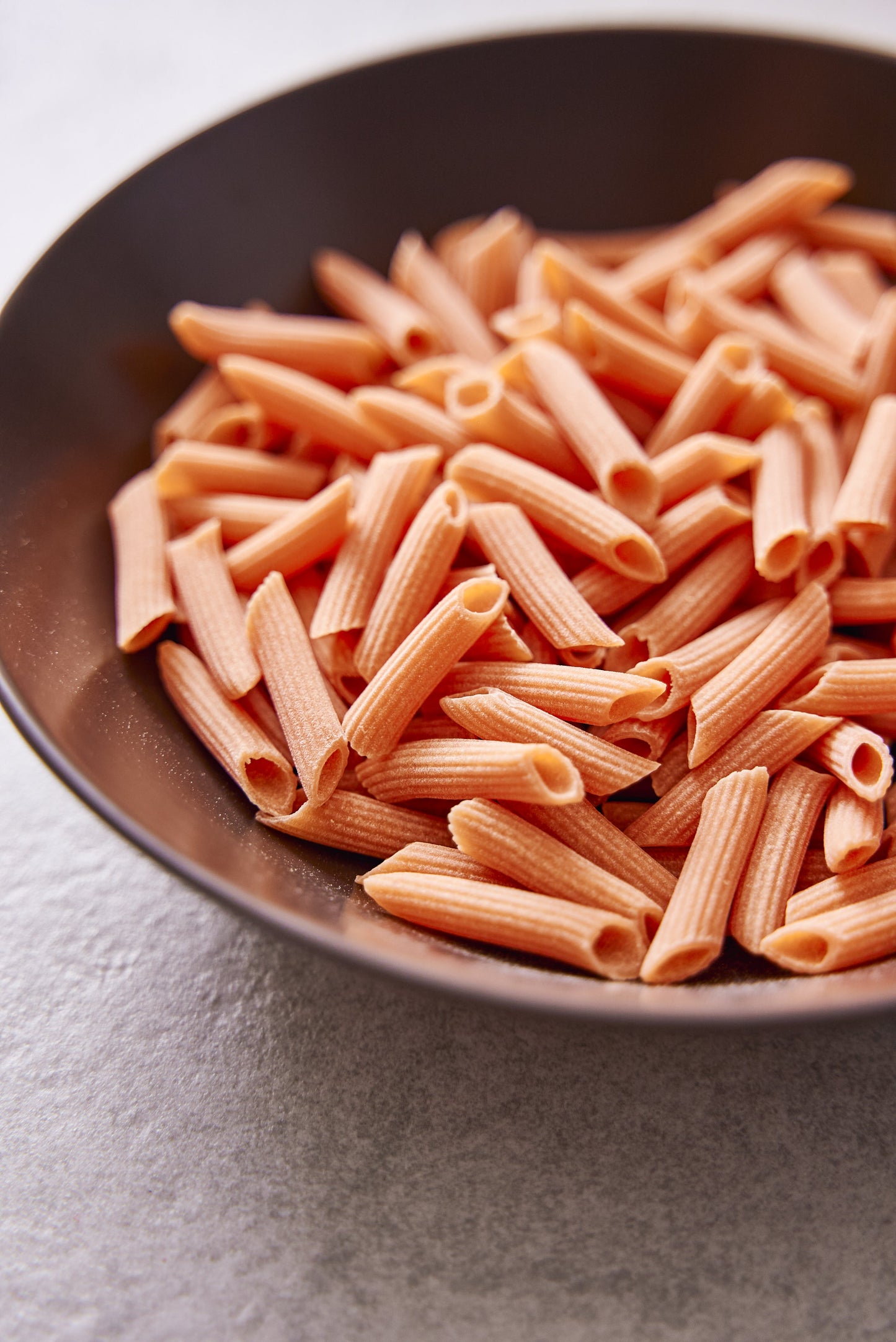 High protein Flower Chef Foods penne pasta in a clear glass bowl, showcasing the short, cylindrical pasta shape.