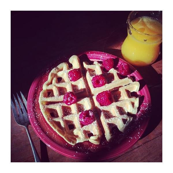 Box of gfJules gluten-free pancake and waffle mix with a scoop of batter and cooking utensils on a wooden surface.