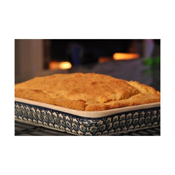Bag of gfJules gluten-free cornbread mix with a scoop and mixing bowl on a wooden countertop, ready for baking.