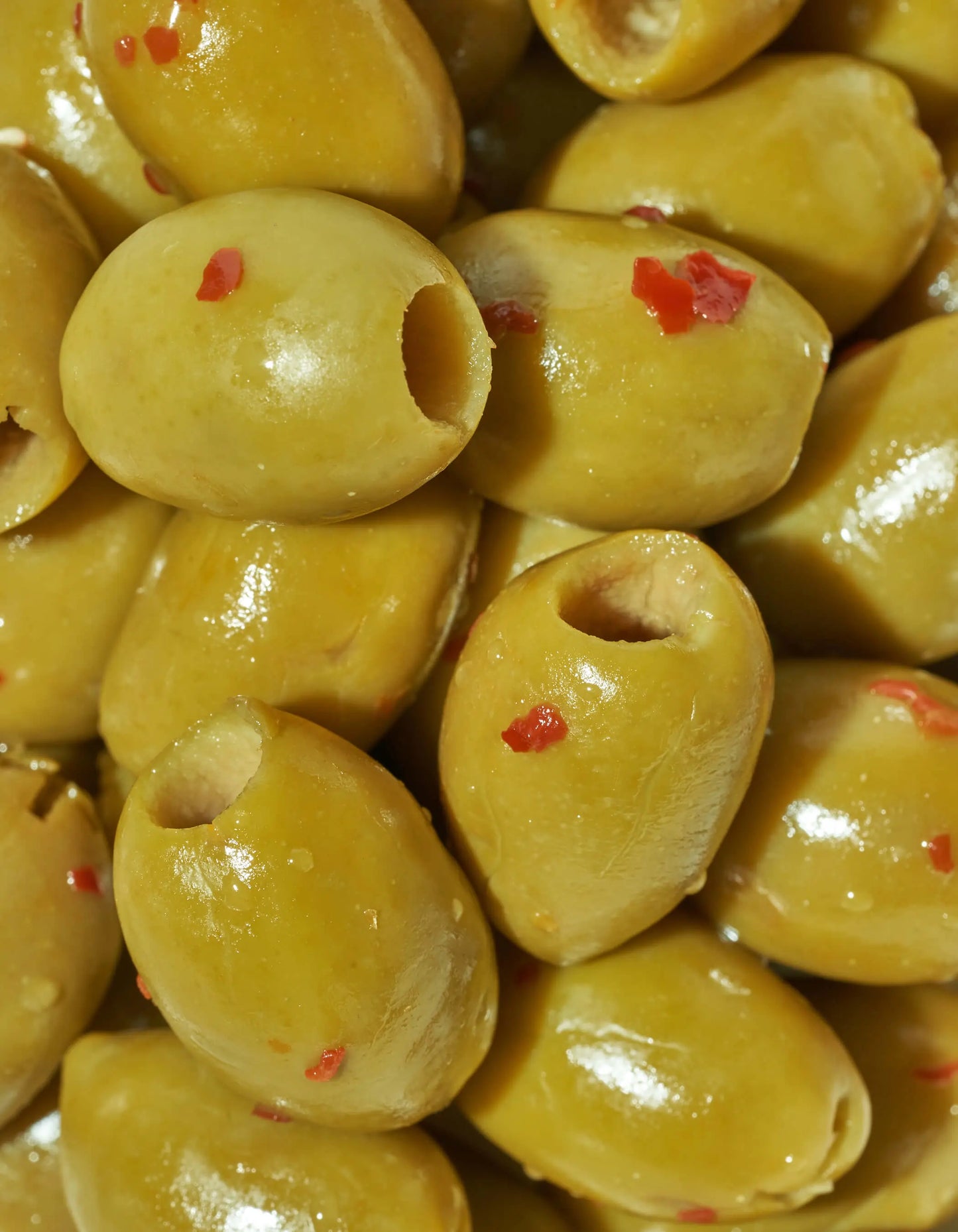 Spicy green olives from FreeStyle Snacks, featuring a vibrant bowl of hot and spicy seasoned green olives on a wooden table.