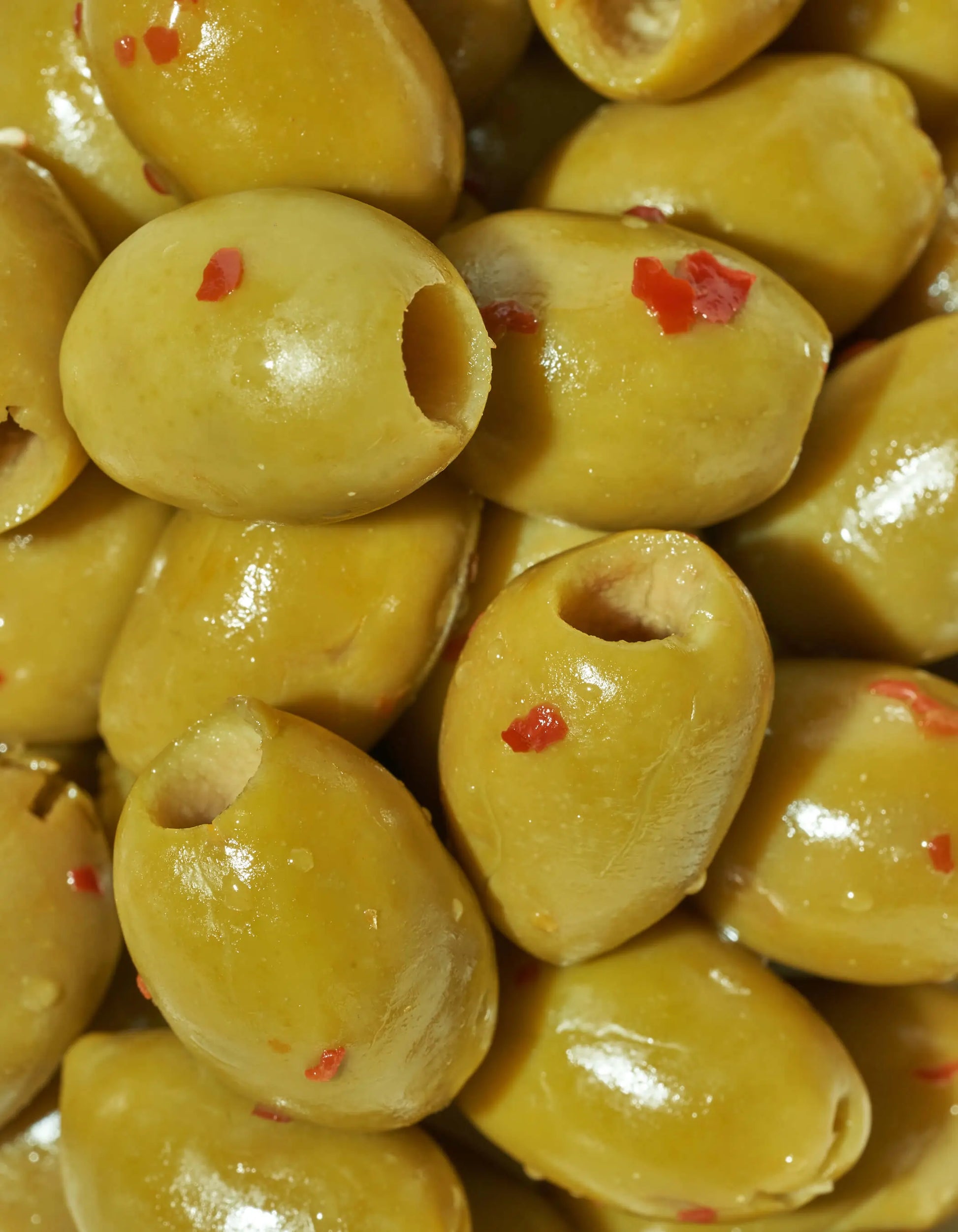 Spicy green olives from FreeStyle Snacks, featuring a vibrant bowl of hot and spicy seasoned green olives on a wooden table.