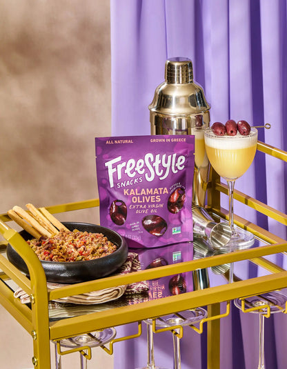 Jar of Freestyle Snacks Kalamata Olives in extra virgin olive oil with visible dark olives and a clear glass jar.