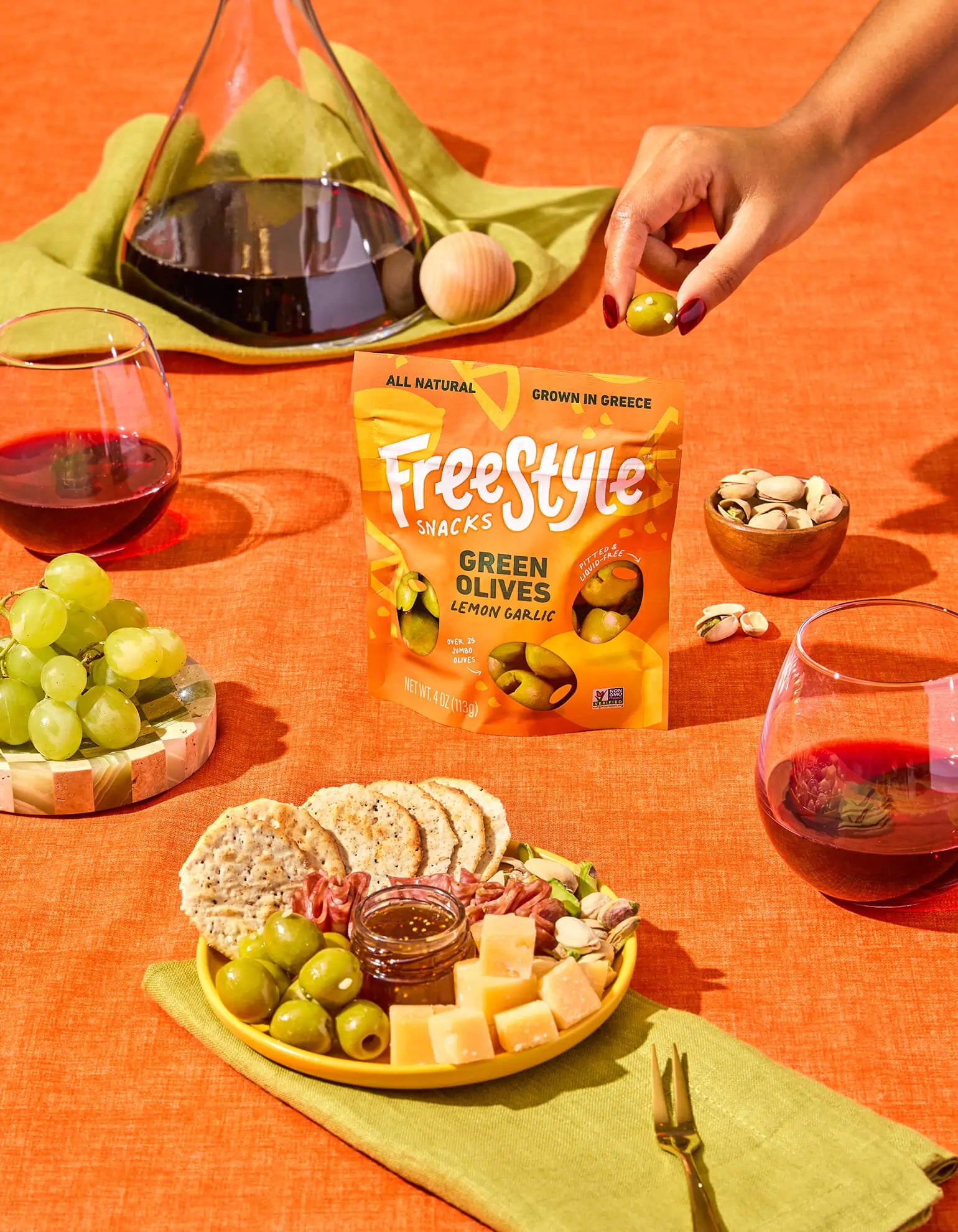 Fresh green olives with lemon and garlic from FreeStyle Snacks, displayed in a clear bowl on a rustic wooden table.