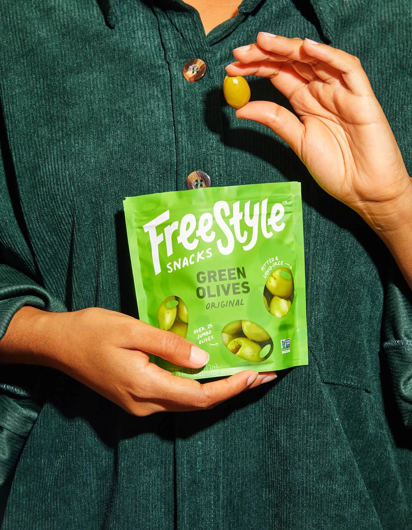 Green olives from FreeStyle Snacks in original flavor, shown in a clear container with vibrant green olives ready to eat.