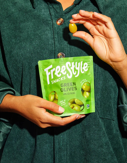 Green olives from FreeStyle Snacks in original flavor, shown in a clear container with vibrant green olives ready to eat.