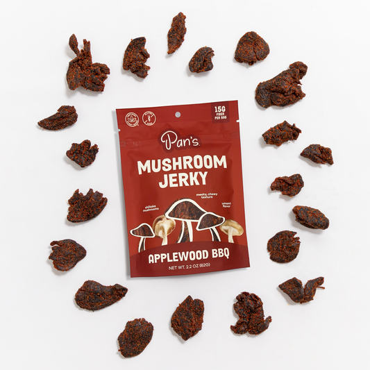 Slices of Pan's Mushroom Jerky Applewood BBQ flavor with smoky glaze and tender texture, displayed on a white surface.