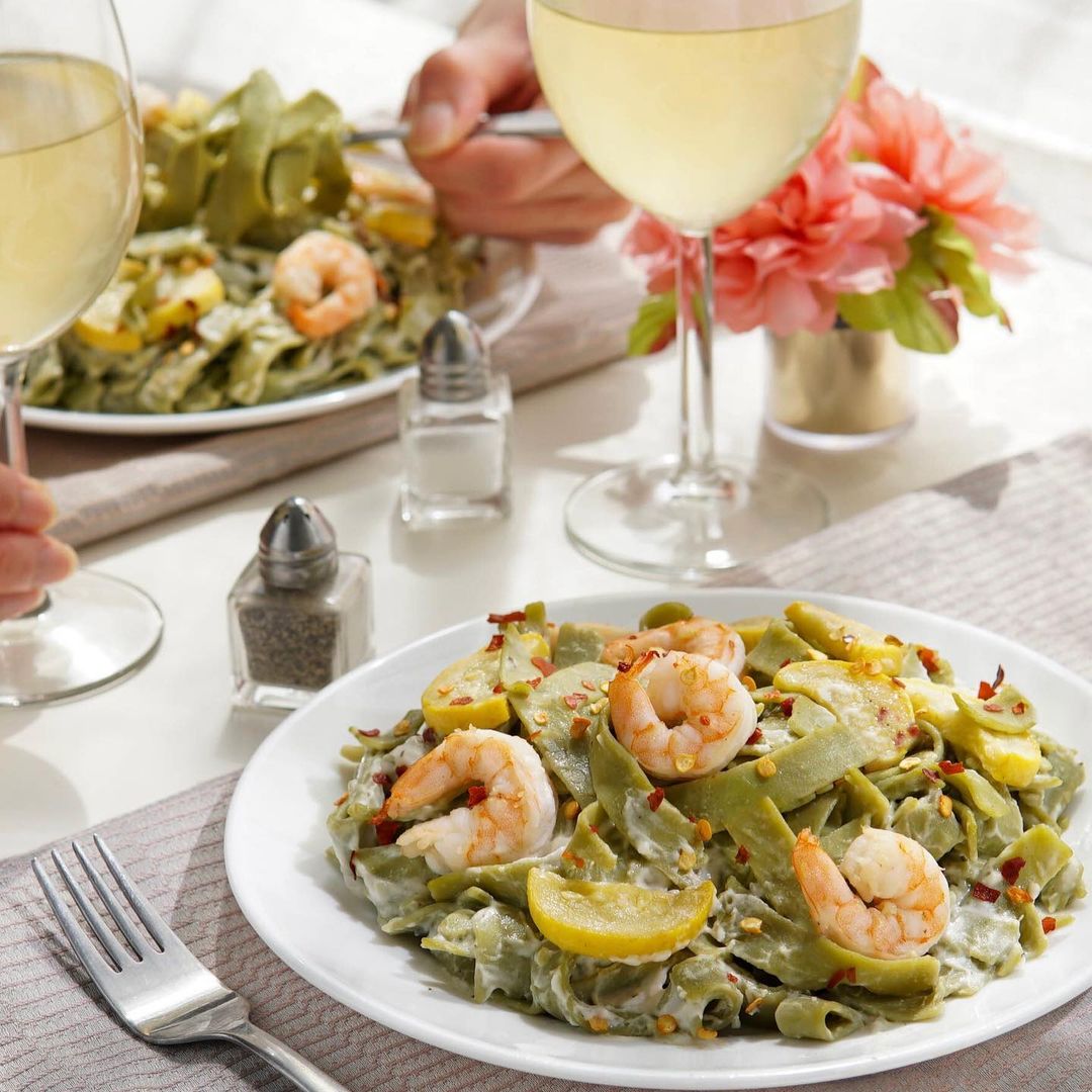 Fresh gluten-free spinach fettuccine pasta by Taste Republic served on a plate with sauce and garnishes.