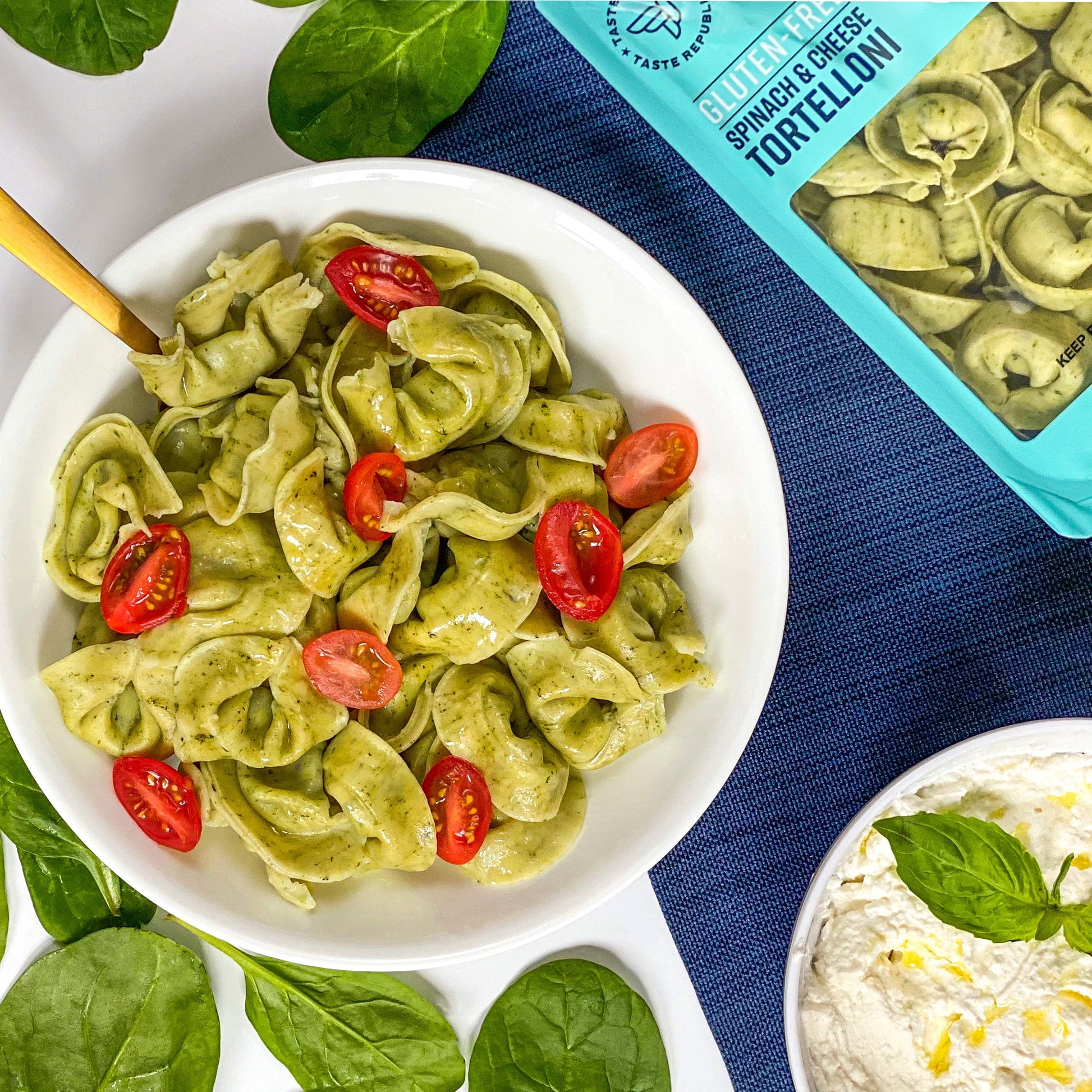 Fresh gluten-free spinach and cheese tortelloni from Taste Republic, served on a plate with basil garnish and surrounding pasta ingredients.