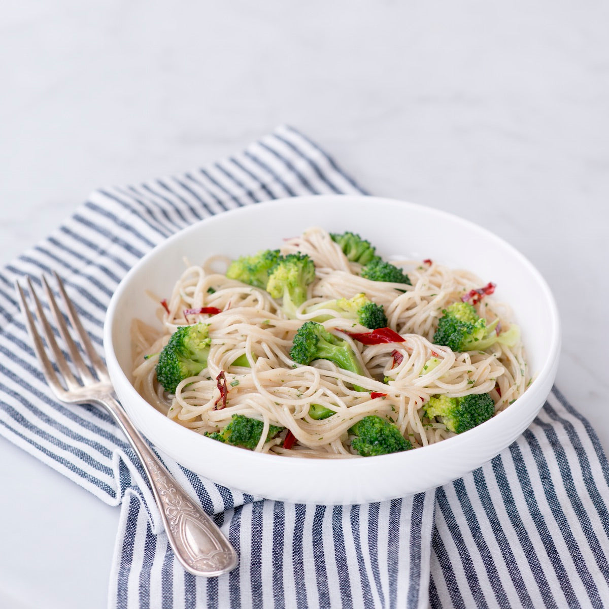 Jovial Gluten Free Brown Rice Capellini pasta, uncooked, showing thin, light brown pasta strands on a white background.
