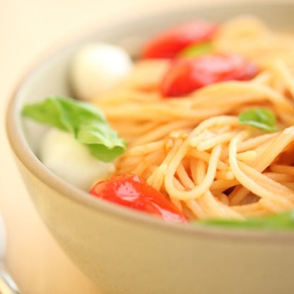 Gluten-free Jovial Brown Rice Spaghetti with cherry tomatoes and fresh herbs on a plate, showcasing a healthy Italian pasta dish.
