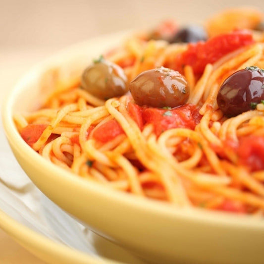 Gluten-free brown rice spaghetti by Jovial Foods, Inc, served with puttanesca sauce in a bowl.