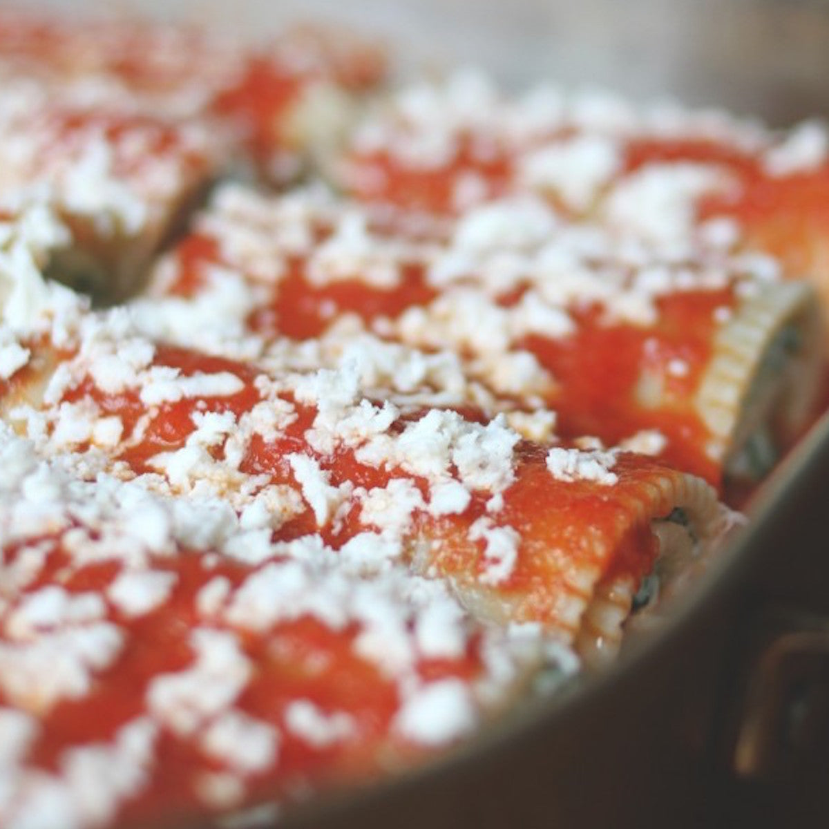 Jovial Gluten Free Brown Rice Manicotti ready to bake, uncooked canelloni filled with ricotta and herbs on a baking dish.