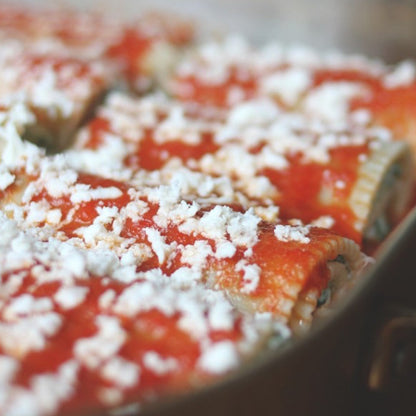 Jovial Gluten Free Brown Rice Manicotti ready to bake, uncooked canelloni filled with ricotta and herbs on a baking dish.