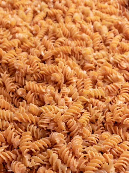 Field of gluten-free and high-protein fusilli pasta from Flower Chef Foods in a 6-pack, displayed outdoors in a field setting.
