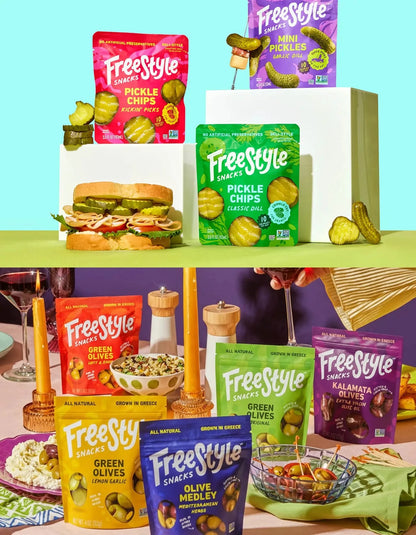 Assorted pickles and olives from FreeStyle Snacks The Party Pack, including jarred pickles and green olives on a platter.