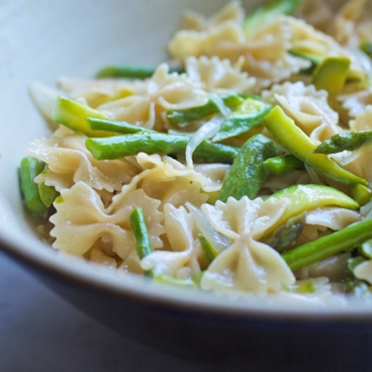 Jovial gluten-free brown rice farfalle pasta in a clear bowl, showing the shape and texture of the pasta.