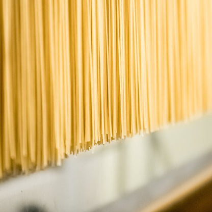 Gluten-free Jovial Brown Rice Fettuccine pasta in a close-up image showing its flat, ribbon-like shape and light brown color.