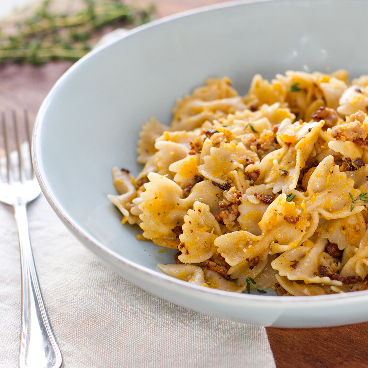 Jovial gluten-free brown rice farfalle pasta with butternut squash, displayed on a plate with fresh herbs and vegetables.