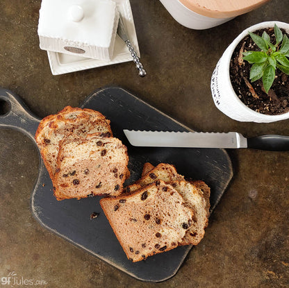 gfJules gluten-free cinnamon raisin bread loaf on a wooden board, showing golden crust and raisin-filled slices.