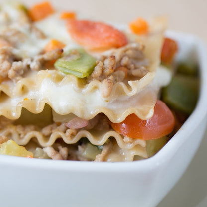 Gluten-free brown rice lasagna by Jovial Foods, Inc, layered with cheese and sauce in a baking dish.