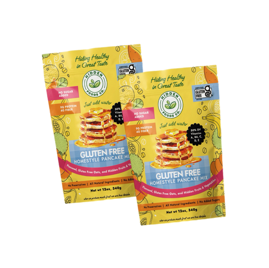 Gluten-free homestyle pancake mix 2-pack from Hidden Foods Co., showing fluffy cooked pancakes with syrup and butter on a plate.