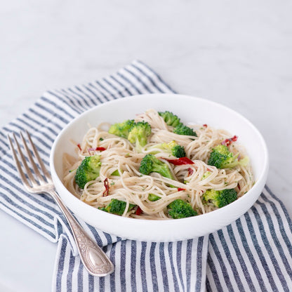 Jovial Gluten-Free Brown Rice Capellini pasta in a clear bowl, highlighting the thin, golden-brown rice noodle strands.
