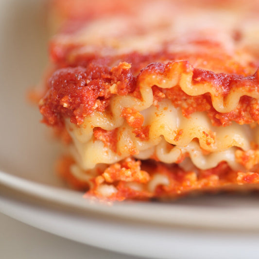 Gluten-free brown rice lasagna by Jovial Foods, Inc, layered with cheese and tomato sauce in a baking dish.