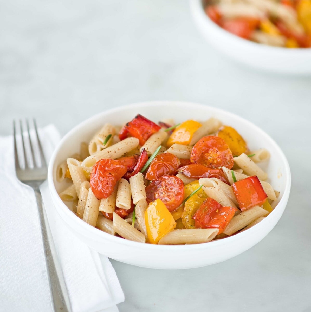 Jovial Gluten Free Brown Rice Penne Rigate pasta in a bowl, showcasing the pasta's shape and texture on a white surface.