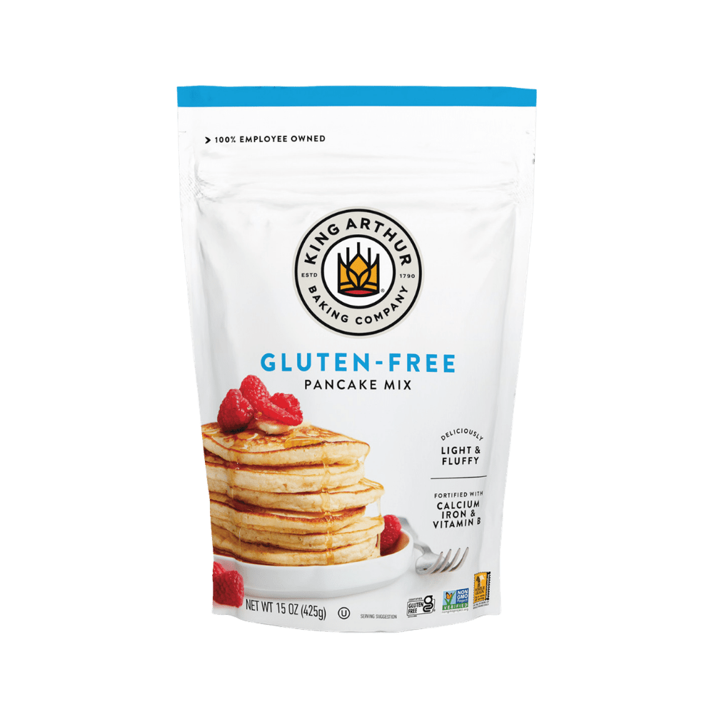 Box of King Arthur Pancake Mix with a scoop of prepared pancakes and syrup on a plate, showcasing the baking product and finished breakfast.