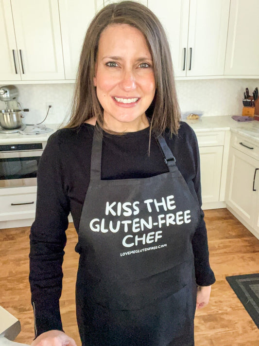 Love Me Gluten Free kitchen apron with adjustable straps, featuring a colorful printed design, ideal for cooking and baking.