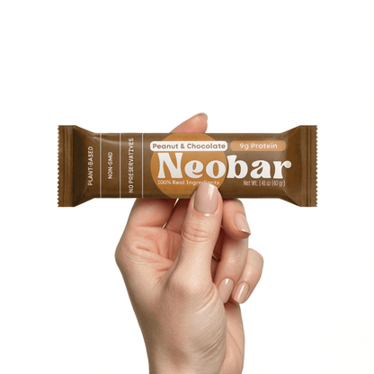 Hand holding a Neobar Peanut & Chocolate protein bar against a white background