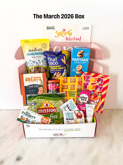 Love Me Gluten Free March 2026 Box featuring assorted gluten-free snacks and treats in a decorative box.